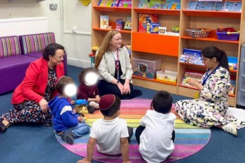Catherine McKinnell  with several children gathered on a classroom rug